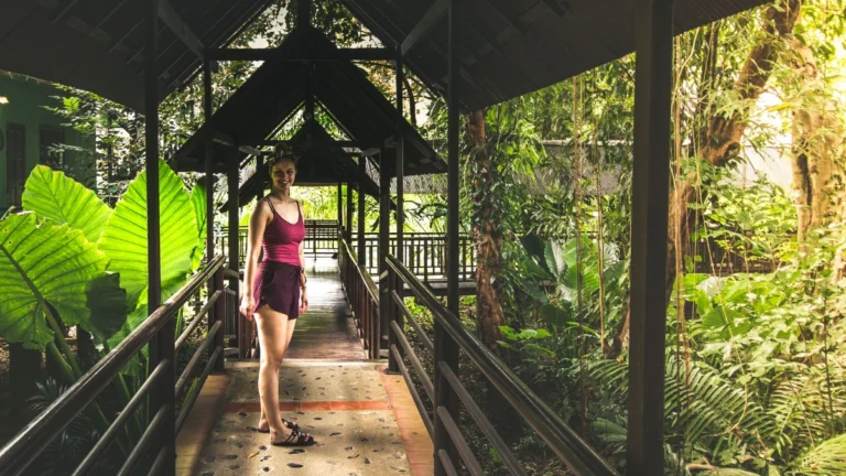 Frau auf überdachtem Holzsteg im tropischen Dschungel in Khao Sok