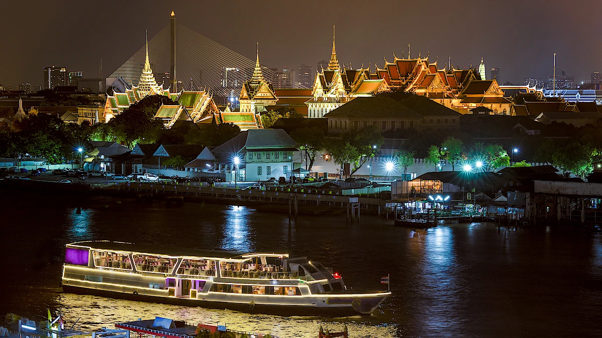 Bangkok dinner cruise boat on the Chao Phraya river in front of the Grand Palace by night